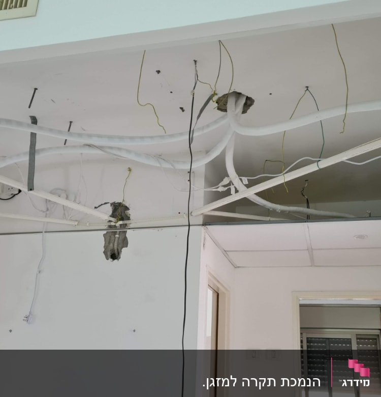 תקרת גבס פתוחה עם חוטי חשמל וצינורות חשופים